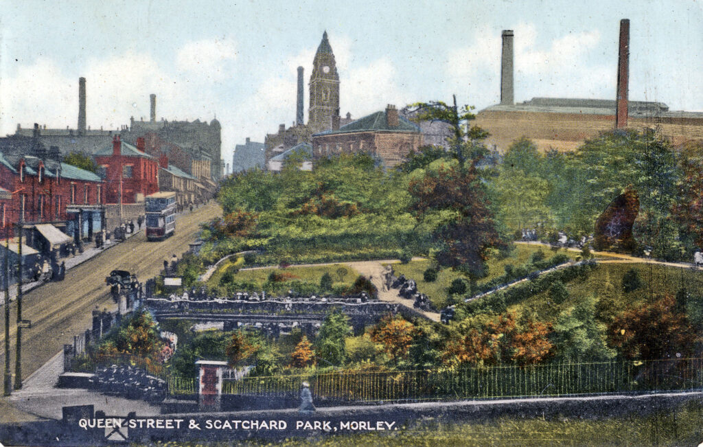 A historical postcard view of Queen Street and Scatchard Park in Morley, showcasing greenery and people enjoying the park, with buildings and chimneys in the background.